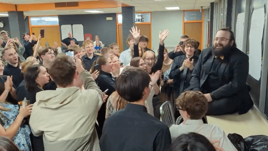 Students cheer as their choir director looks into the crowd with a smile.