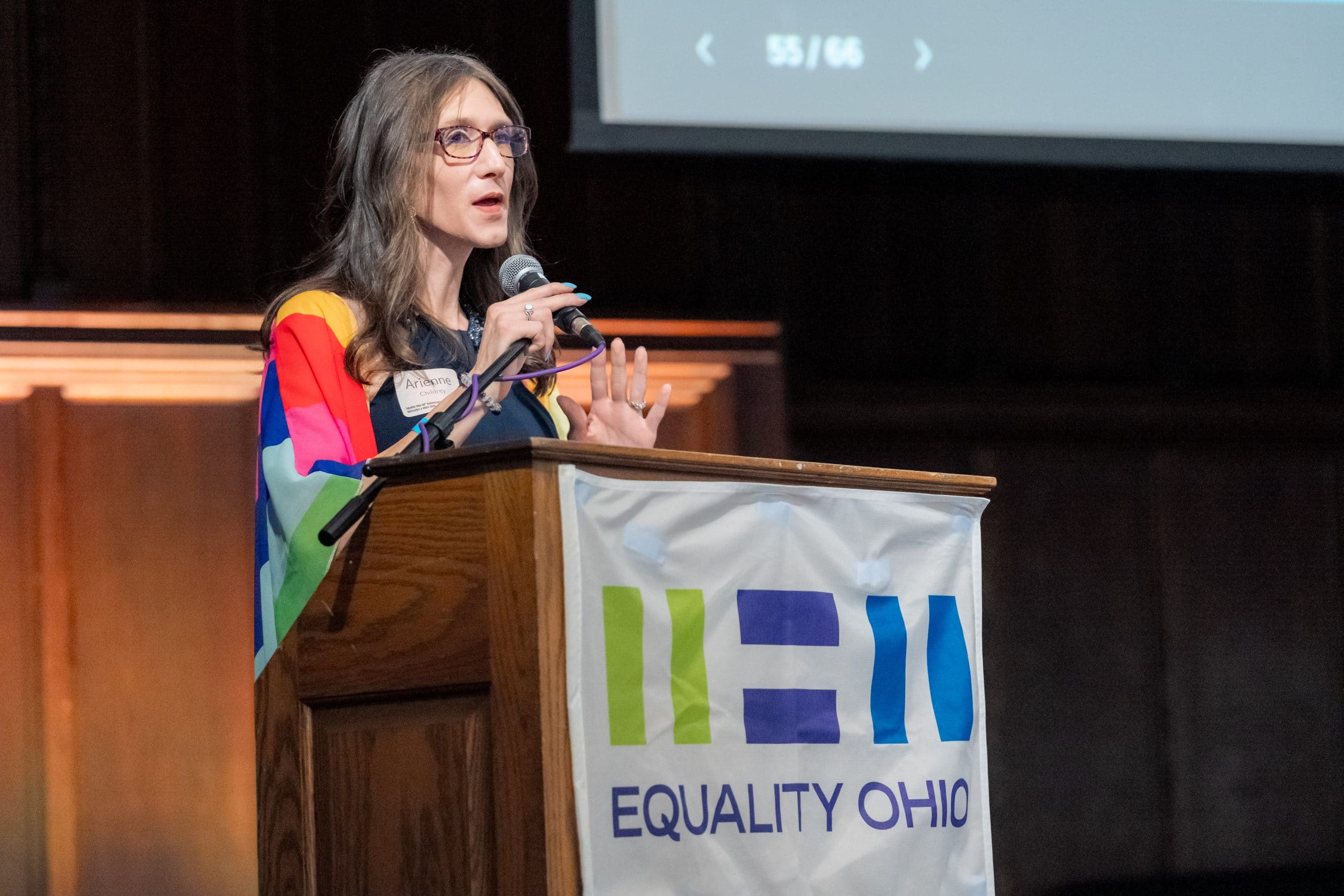 Transgender candidate for the Ohio statehouse Arienne Childrey speaks at a podium with an Equality Ohio banner draped in front.