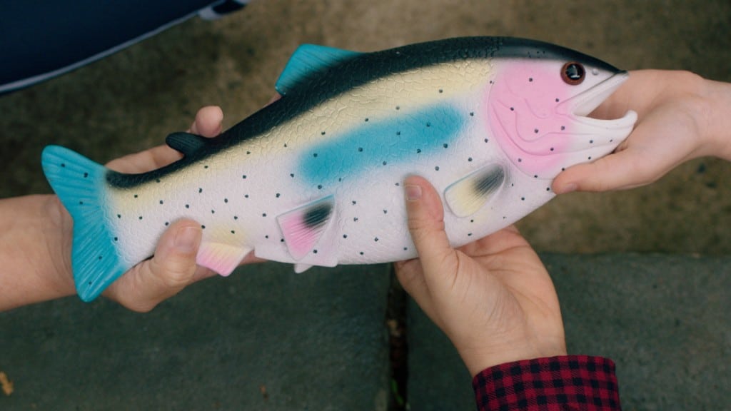 Unseen people hold a big plastic fish.