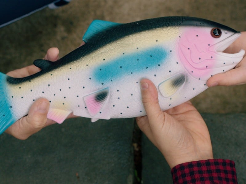 Unseen people hold a big plastic fish.