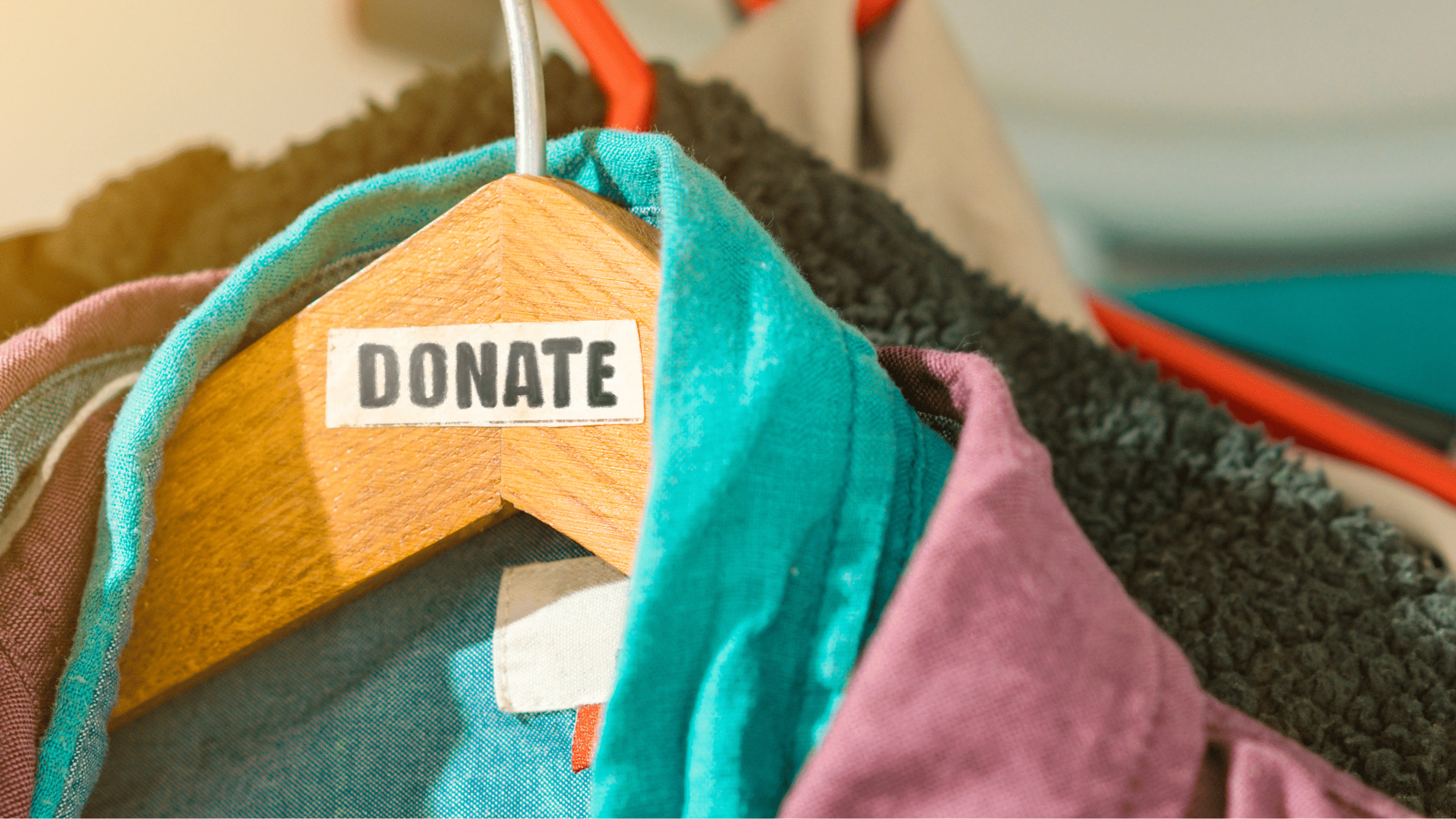 The stock image shows clothes in (coincidentally) trans Pride colors hanging on a wooden hangar. A label is on the hangar that reads "DONATE."