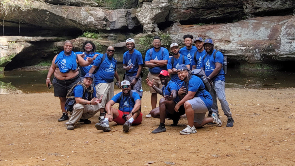 Attendees of Black Trans Men of Ohio pose for a group photo at a rock formation.