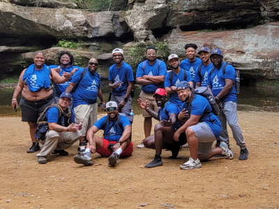 Attendees of Black Trans Men of Ohio pose for a group photo at a rock formation.