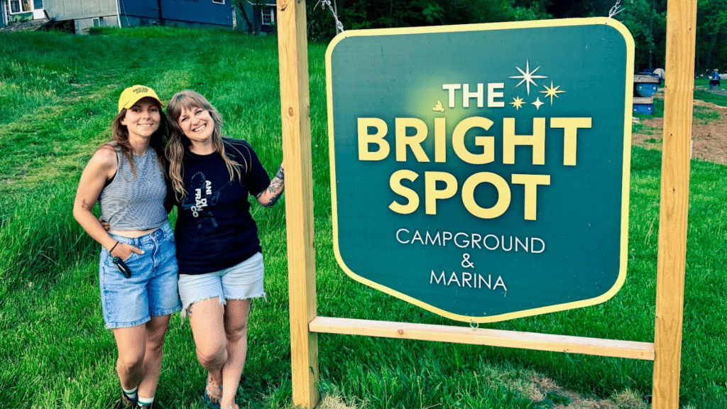 Tessa and Chelsea Pratt-Smith pose in front of the sign for their queer-friendly business called The Bright Spot Campground and Marina.