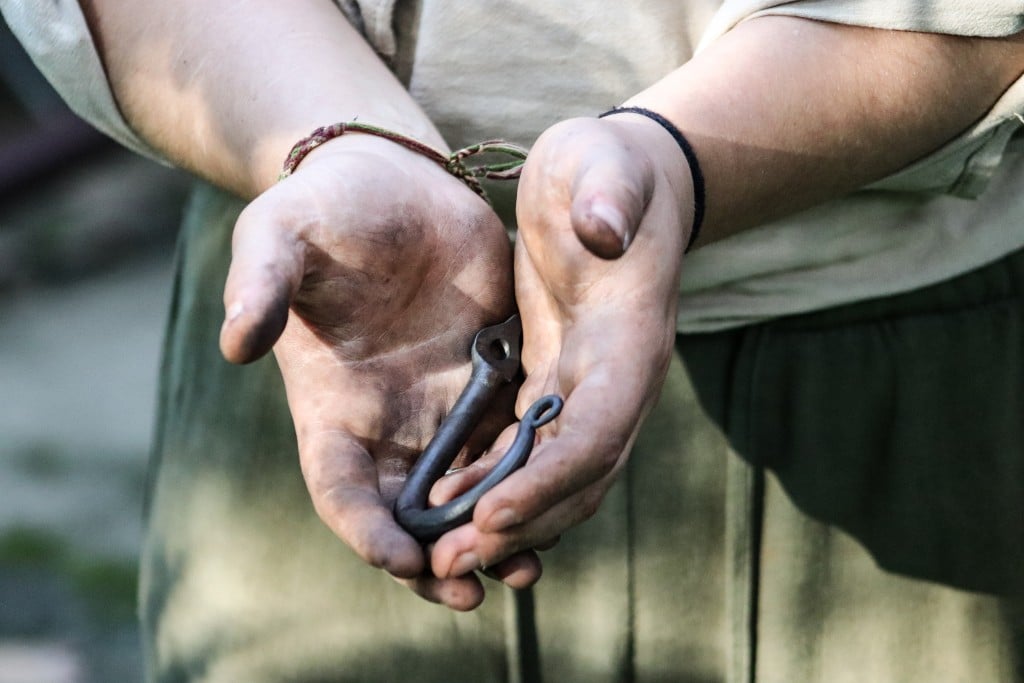 Rose Solomon, a trans blacksmith, holds a leaf-like J-hook in her hands smudged with soot.